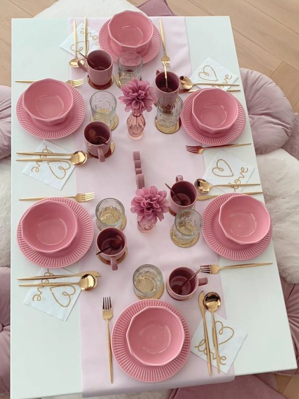 Roze feesttafel met gouden bestek en bloemen