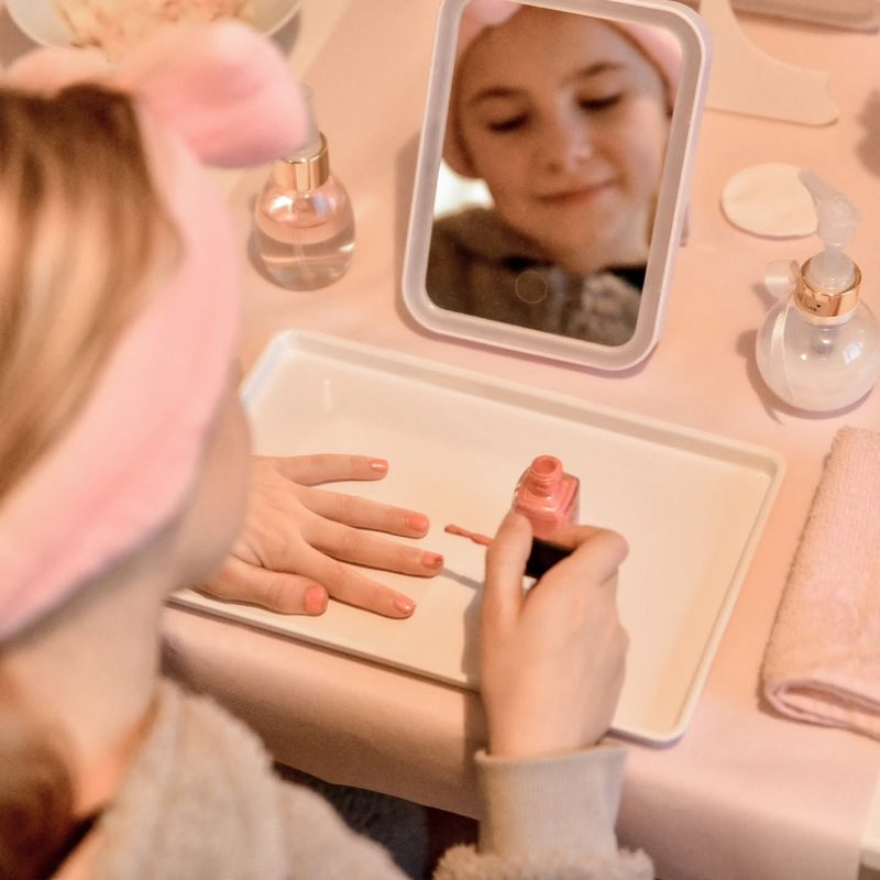 Meisje kijkt in een spiegeltje bij de beautyhoek