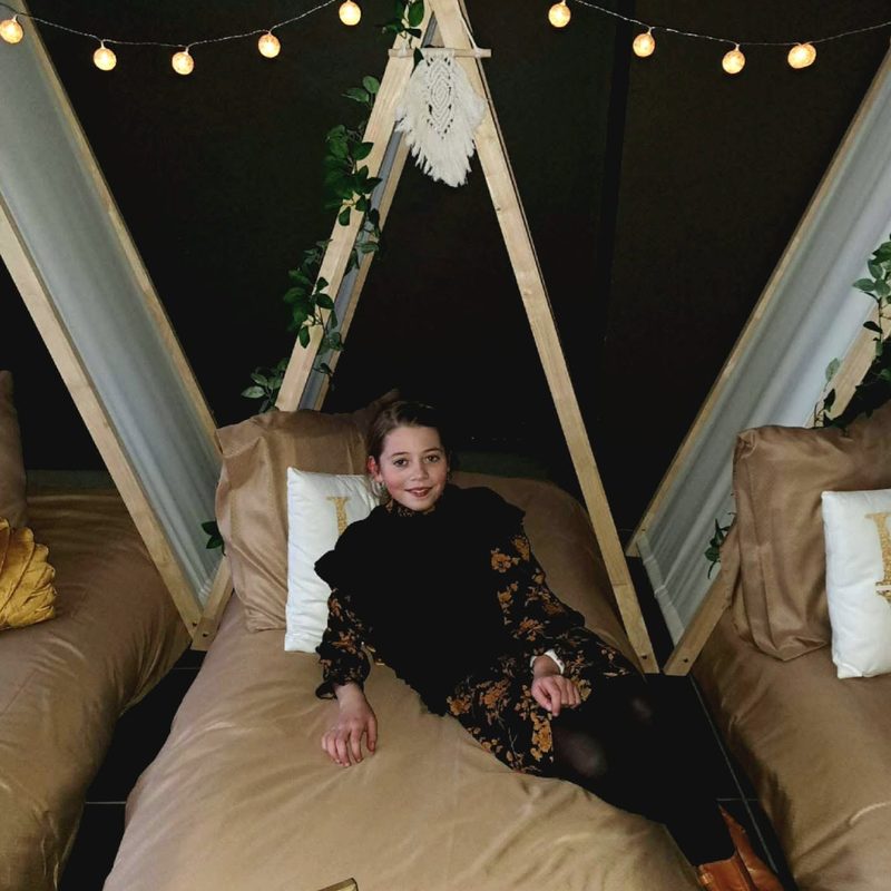 Meisje lacht in een tipi-tent met lichtjes