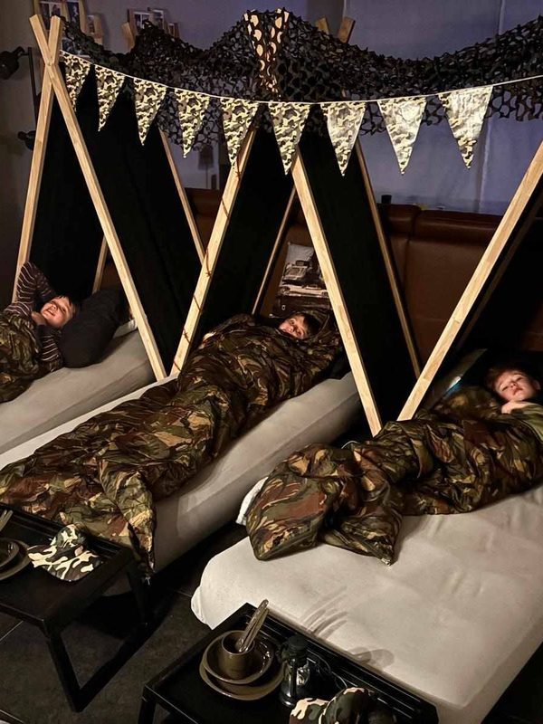 Kinderen in camouflagebedjes onder een camouflagenet